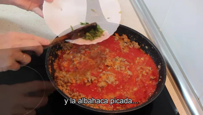 Agregar el tomate triturado o rallado y la albahaca picada. Tapar y dejar cocinar hasta que la salsa haya reducido.