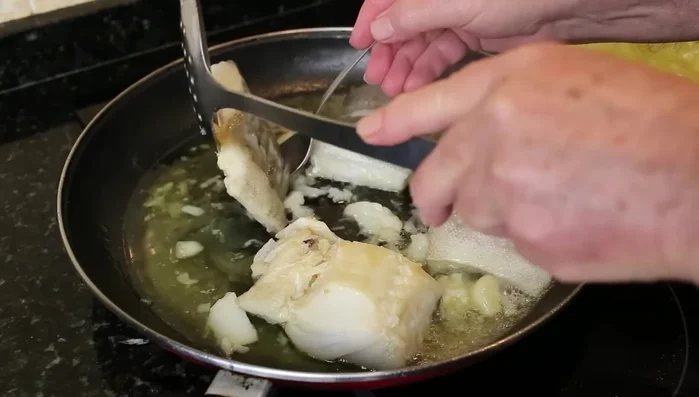 Dar la vuelta al bacalao a los 15 minutos. Agregar los langostinos crudos y pelados tras 10 minutos más. Remover.