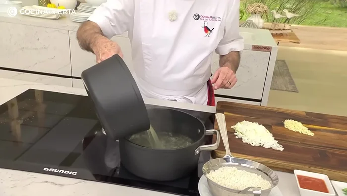 Añadir al caldo el arroz lavado, la cebolleta picada, el ajo picado, la salsa de tomate, el comino, la guindilla, el colorante, la hoja de laurel y el orégano. Salpimentar ligeramente (ya que el caldo contiene sal). (290.639)