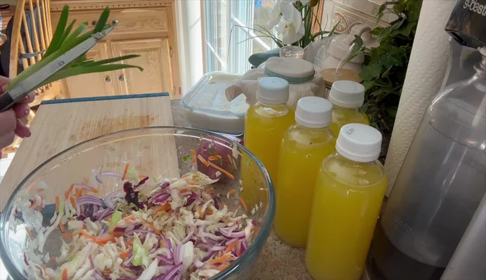 Agregar el repollo blanqueado, la cebolla morada, la cebolla verde y el aderezo a un recipiente grande. Mezclar bien.