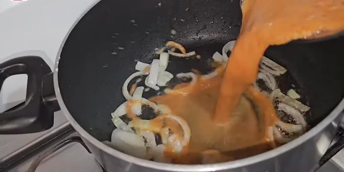 Agrega la salsa licuada a la olla con la cebolla sofrita. Enjuaga el vaso de la licuadora con el agua de cocción de los jitomates y agrégala a la olla.