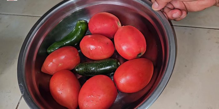 En una olla con agua hirviendo, agrega un trozo de cebolla, 3 dientes de ajo, los 7 jitomates y los chiles. Cocina por 10 minutos.