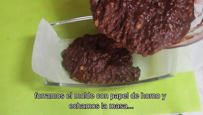 Verter la masa en un molde forrado con papel de horno, igualar la superficie y decorar con las pepitas de chocolate reservadas.
