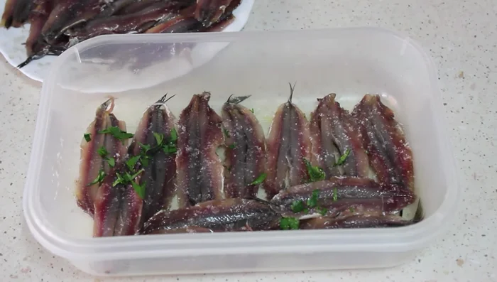 Añadir sal y perejil picado entre capas de boquerones.
