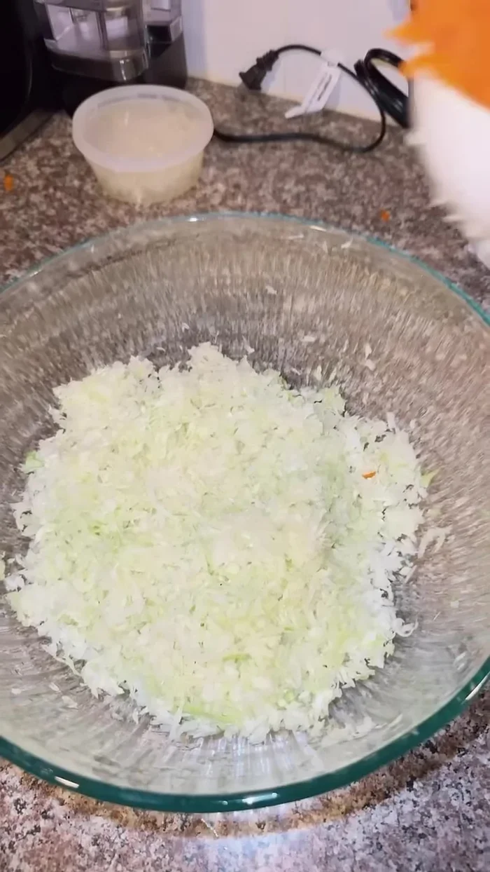 Combinar ingredientes: En un recipiente grande, mezclar las cuatro tazas de repollo rallado, dos tazas de zanahoria rallada, las cebollas marinadas y la mezcla de crema de leche y azúcar.