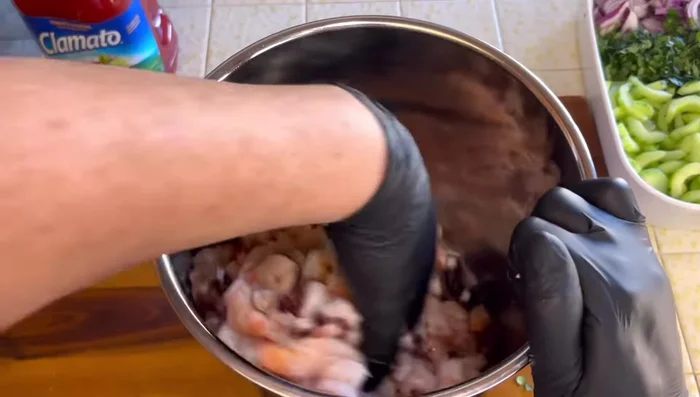 Mezclar los ingredientes: En un recipiente grande, combinar el pulpo, los camarones, la cebolla morada, el pepino, el cilantro, el caldo de camarones, el caldo de pulpo, el clamato, el kétchup, el jugo de limón, la salsa tabasco, la sal, la pimienta molida, la salsa Maggi y la salsa inglesa.
