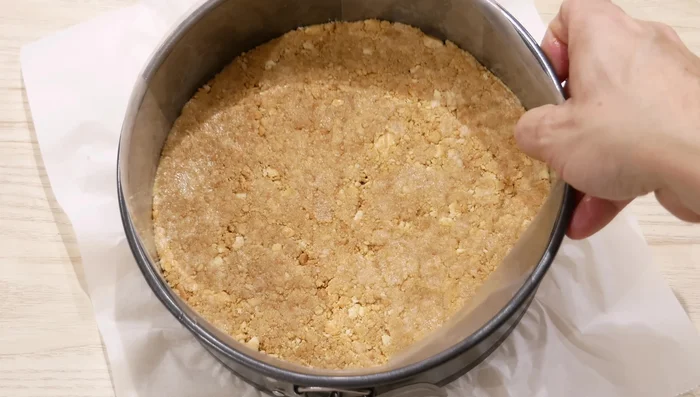 Presiona la mezcla de galletas en la base del molde forrado. (61.399)