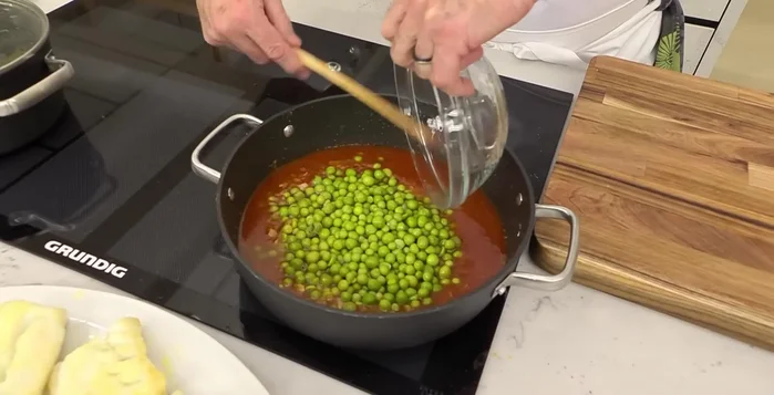 Agregar los guisantes cocidos y el bacalao dorado con su jugo a la cazuela.