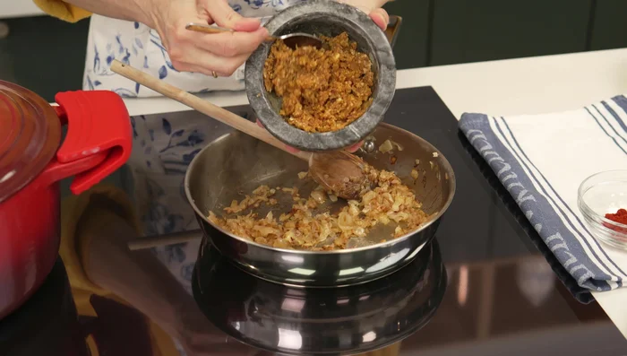 Añadir la majada al sofrito de cebolla, mezclar e incorporar el pimentón.