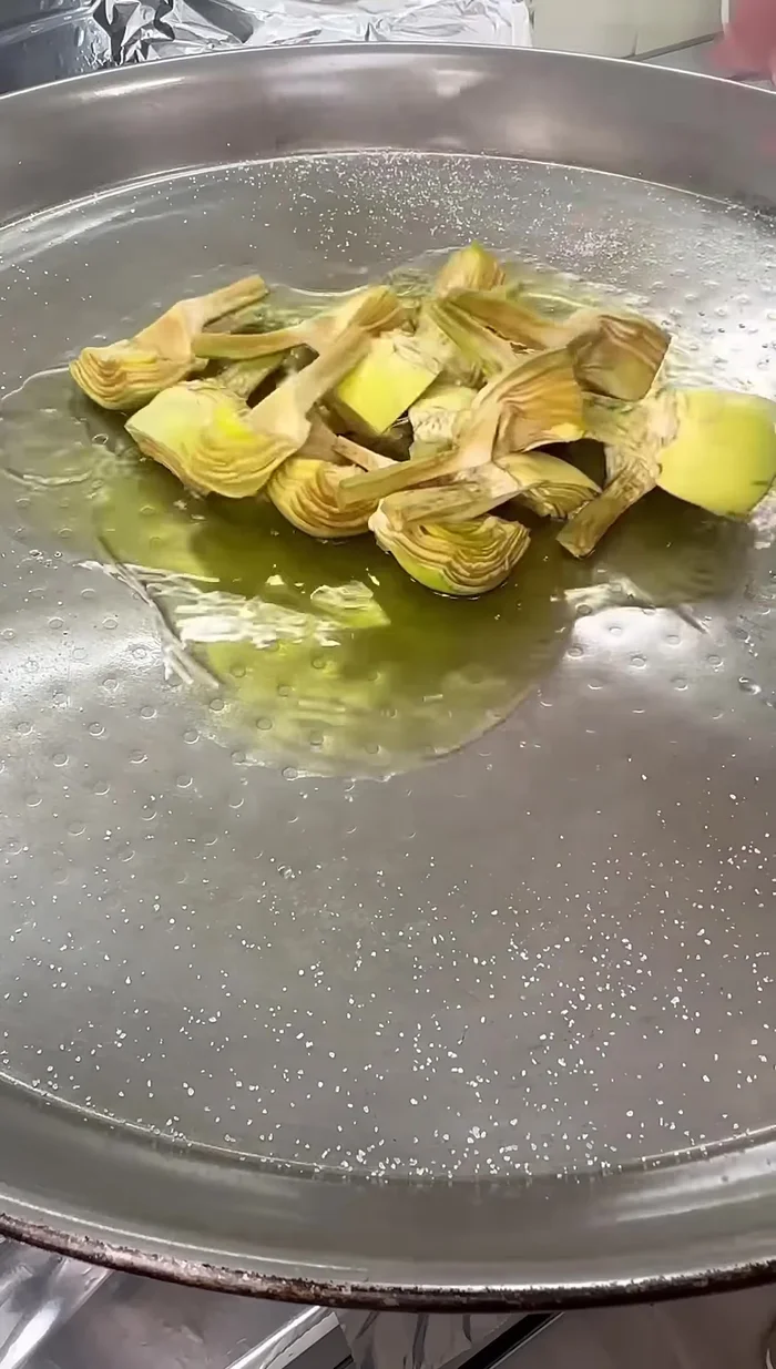 En la paella, sofreír las alcachofas con aceite de oliva hasta que estén cocinadas. Reservar.