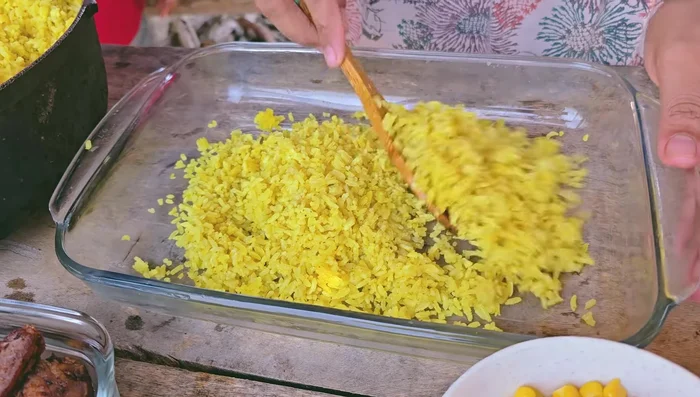 Armar el arroz montañero: en un recipiente grande, mezclar capas de arroz, costilla, chorizo, tocineta, chicharrones, maíz tierno, plátano frito, y el hogado.