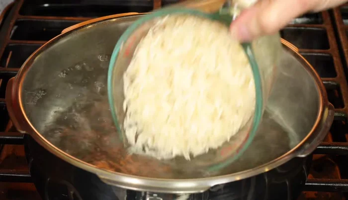 Agrega sal y una gota de aceite al agua hirviendo con el arroz. Lleva a ebullición, baja el fuego a medio y cocina hasta que esté tierno (10-15 minutos).