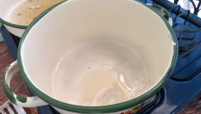 Colar la mezcla licuada para eliminar las semillas y especias. Agregar el jitomate colado a una cacerola con un poco del aceite donde se frieron las tortitas, junto con cebolla, un cubo de consomé de tomate y agua.