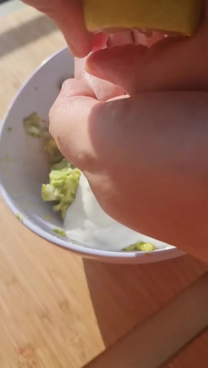 Agrega el yogurt griego, jugo de limón, sal y pimienta al puré de palta. Mezcla bien.