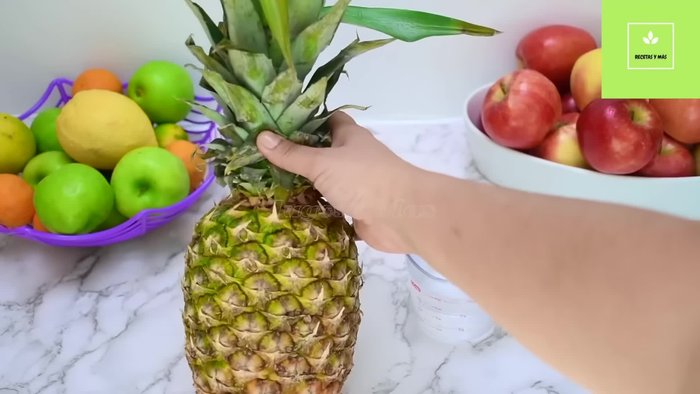 Preparación de la mermelada de piña: Cortar la piña en trozos pequeños, descartando la parte central dura. Reservar la corona para decorar.