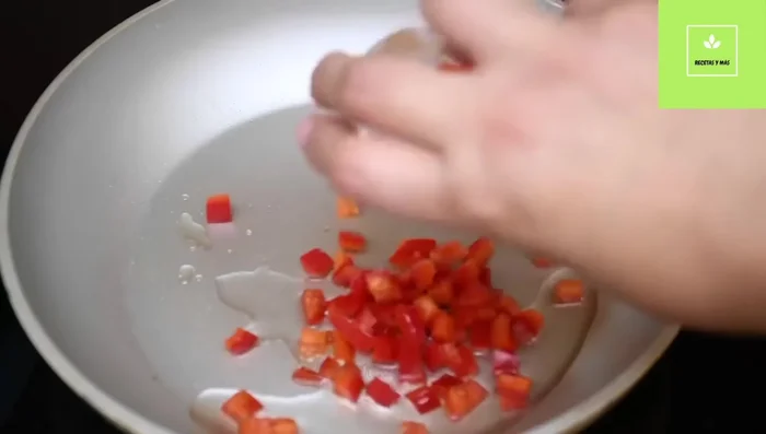 Preparación de los huevos con verduras: Sofreír los pimientos rojo y verde a fuego medio-alto durante 30 segundos a 1 minuto.