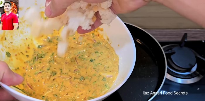 Agregar porciones de la mezcla de pakora a la sartén caliente, incorporando los trozos de pan directamente al aceite caliente sin mezclarlos previamente con la masa. Esto evitará que el pan se vuelva blando.