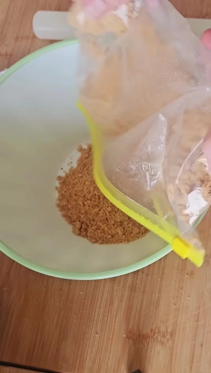 Machacamos las galletas hasta hacerlas polvo (29.359). Mezclamos con mantequilla derretida (35.399). Ponemos la mezcla en el molde, aplastamos bien y refrigeramos para que endurezca (37.239).
