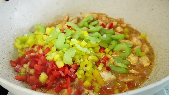 Agregar el pimentón rojo, pimentón amarillo y apio. Cocinar hasta que estén tiernos.