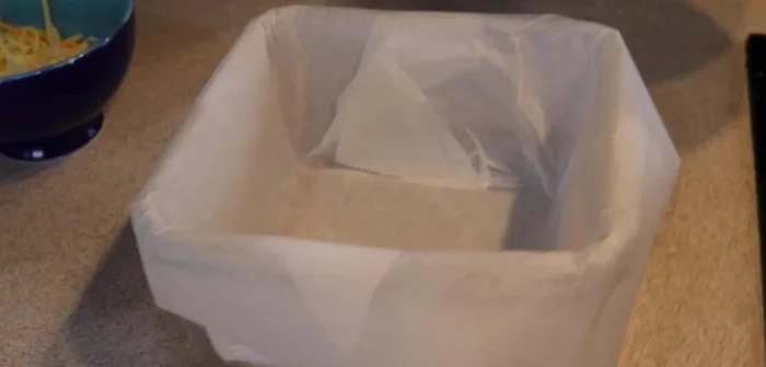 Verter la mezcla en un molde de cristal forrado con papel de horno. Dar forma uniforme y añadir un poco más de queso por encima.