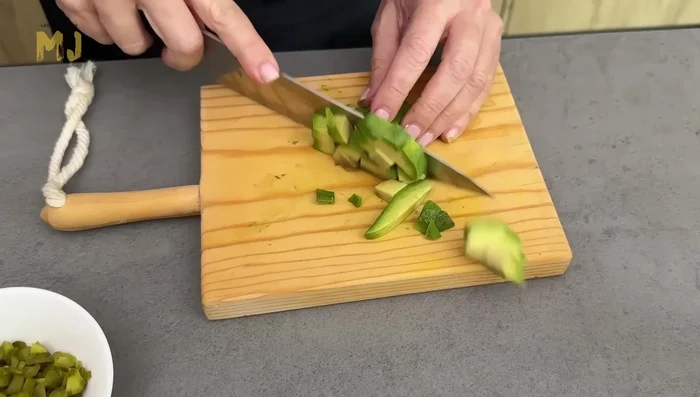 En un bol, mezclar las patatas, los huevos, el aguacate (con zumo de limón para evitar la oxidación), la cebolleta picada, los pepinillos picados y el pollo frío. Salar.
