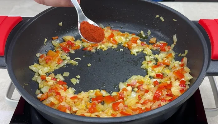 Hacer un hueco en el sofrito, añadir pimentón dulce y remover rápidamente. Incorporar el tomate rallado y el vino blanco, dejar evaporar el alcohol.