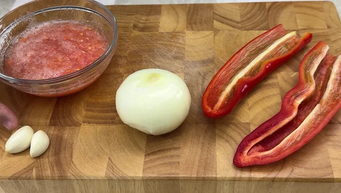 Picar en brunoise el pimiento rojo, la cebolla y los ajos. Rallar el tomate.
