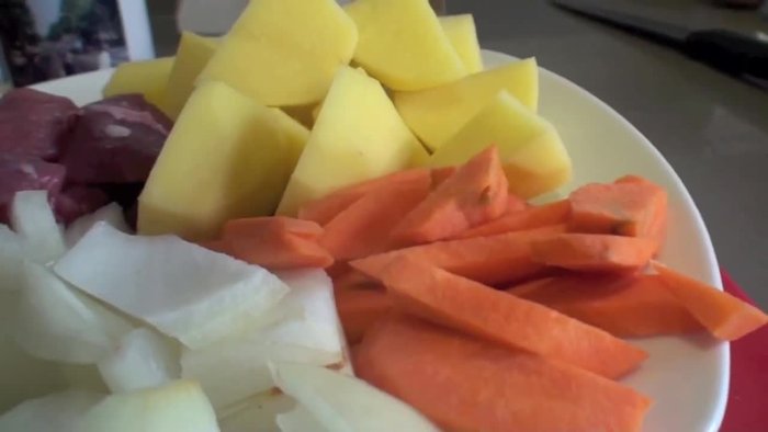 Cortar las patatas a cachelo, la zanahoria a rodajas (mitad de cada rodaja), la cebolla a la mitad y los dientes de ajo por la mitad. Enharinar la carne previamente sazonada con sal y pimienta.