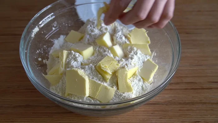 Triturar 130 g de mantequilla (o margarina) con la harina hasta obtener una miga.