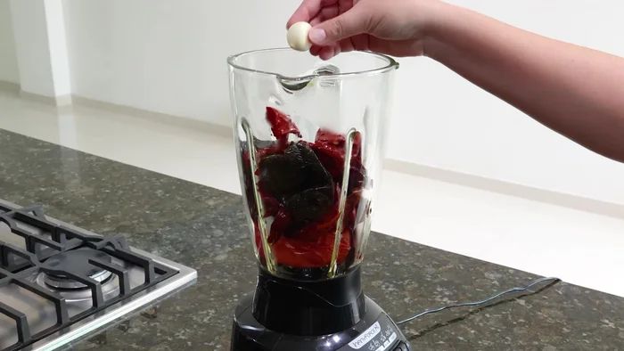 Una vez frío, licúa los chiles cocidos con 1 diente de ajo, 2 clavos de olor, una pizca de comino, 1 cucharada de consomé de pollo, una pizca de pimienta negra molida, 1 cucharadita de sal y 1/2 taza de agua (150.12).
