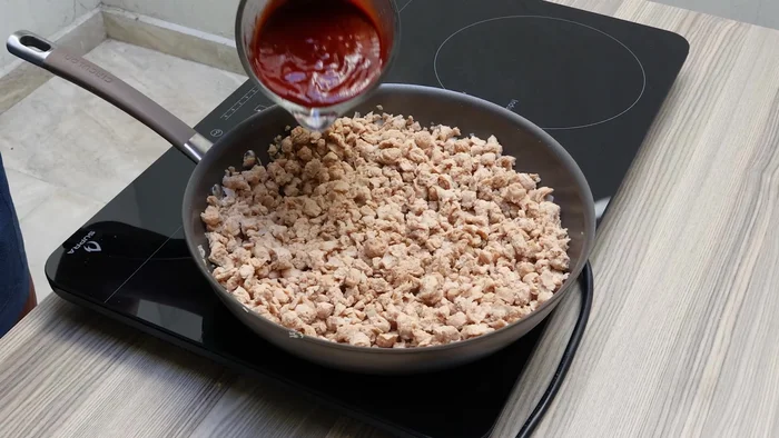 Vierte la salsa de chile sobre la soya y mezcla hasta que el sabor se haya incorporado (234.12).