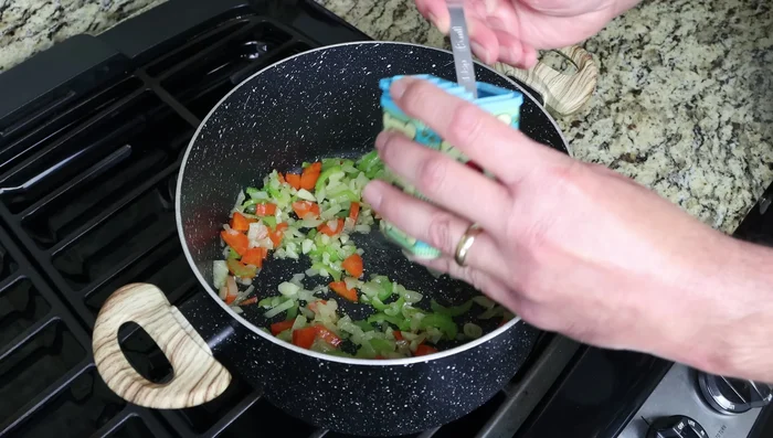 Agregar las especias (pimentón, comino, cúrcuma, jengibre, canela, hojuelas de pimiento rojo). Mezclar bien y saltear brevemente.