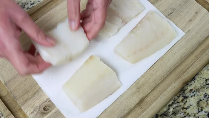 Secar los filetes de bacalao con toallas de papel y sazonarlos con sal y pimienta.