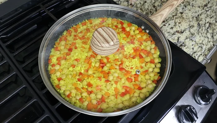 3 minutos antes de que el arroz esté listo, agrega los guisantes congelados. Mezcla bien y tapa la sartén.