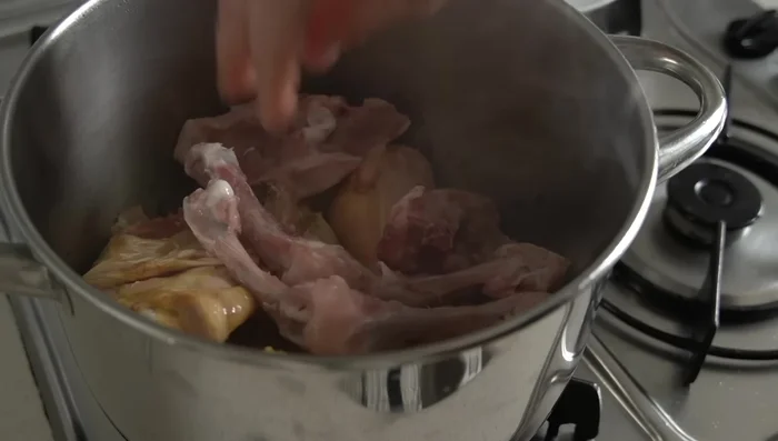 Añadir huesos de pollo (opcional) y cubrir con agua. Llevar a ebullición a fuego alto, luego desespumar antes de que hierva completamente.