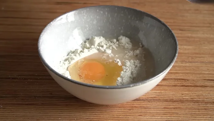 Preparar la masa de la pasta: mezclar harina, huevo y agua hasta obtener una consistencia líquida pero no totalmente fluida.