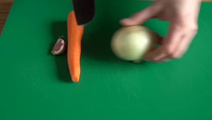 Cortar la cebolla en cuatro (dejando la raíz unida). Cortar la zanahoria en bastoncitos. Dar un golpe al diente de ajo sin pelarlo.