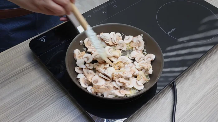 Agregar los champiñones cortados a la sartén y mezclar con una espátula hasta que estén cocidos (unos minutos).