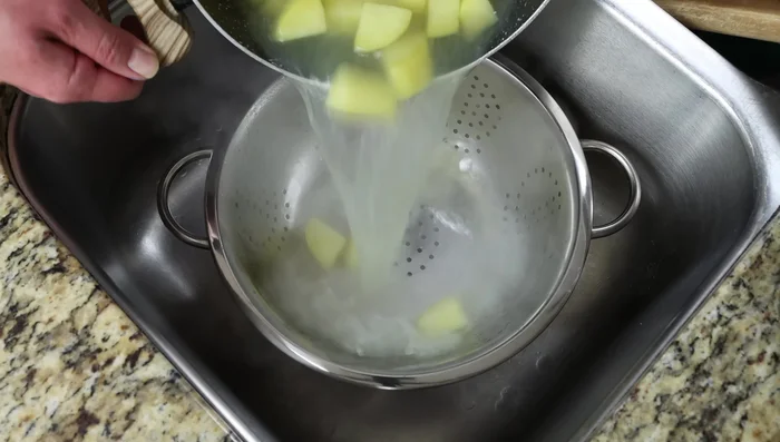 Escurrir las papas cocidas y añadirlas suavemente a la sartén con la salsa cremosa de ajo. Mezclar con cuidado.