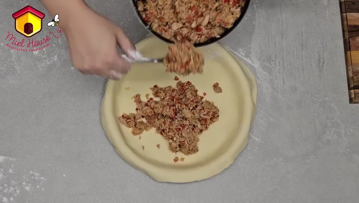 Colocar el relleno sobre la base de la tarta. Cubrir con la tapa de masa y sellar los bordes. Decorar con repulgues o recortes de masa con un sacabocados (opcional). (437.72 - 539.92)