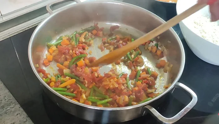Agregar el arroz redondo al sofrito. Incorporar el caldo de langostino y caldo de marisco (o agua adicional si es necesario).
