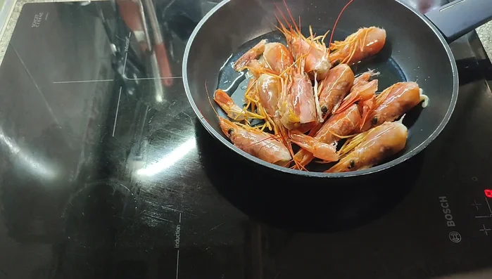 Preparar el caldo: Sofreír las cabezas de langostino en aceite de oliva, aplastándolas para liberar su sabor. Agregar ron (opcional, flambear con cuidado) y agua. Cocinar y colar.