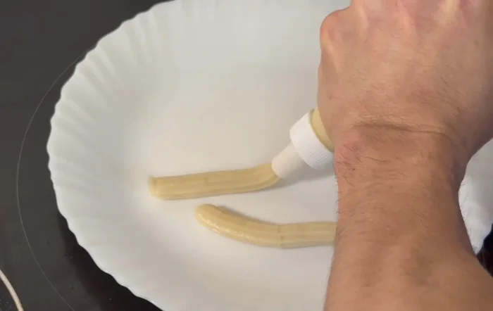 Utilizando una manga pastelera o churrera, formar los churros y freírlos en el aceite caliente, volteándolos con unas pinzas hasta que estén dorados.