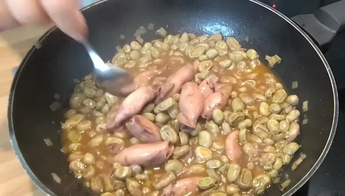Apartar algunos calamares al centro y añadir un huevo por persona encima de las habas.