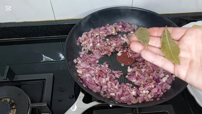 Añadir las hojas de laurel y el pimentón a la cebolla pochada. Mezclar con cuidado. (209.959)