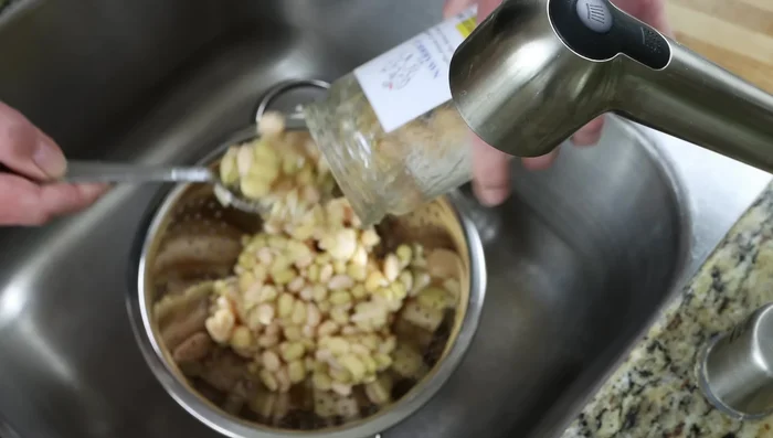 Escurrir los frijoles y enjuagarlos. Agregarlos a la sartén junto con el caldo de verduras y la hoja de laurel (212.08).