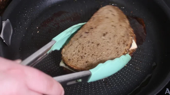 Fundir el queso: Colocar una rebanada de pan en la sartén, añadir queso Raclette y cubrir con otra rebanada. Dorar hasta que el queso se derrita.