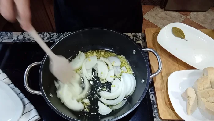 Añade la cebolla cortada en juliana y un poco de sal para que suelte su jugo. Incorpora el pimiento verde cortado en tiras.