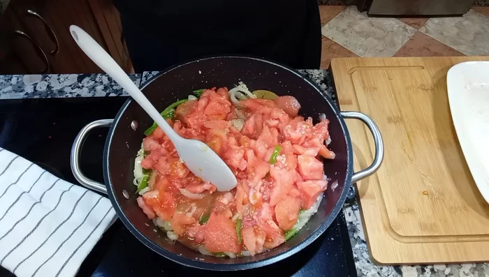 Agrega el tomate troceado al sofrito. Remueve, machaca y sazona con sal. Cocina hasta que el tomate se ablande (aprox. 10 minutos).