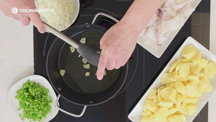 En una cazuela, con un buen chorrito de aceite de oliva virgen extra, añade los ajos picados, la cebolla y el pimiento verde. Sofríe unos minutos hasta que la cebolla esté transparente.